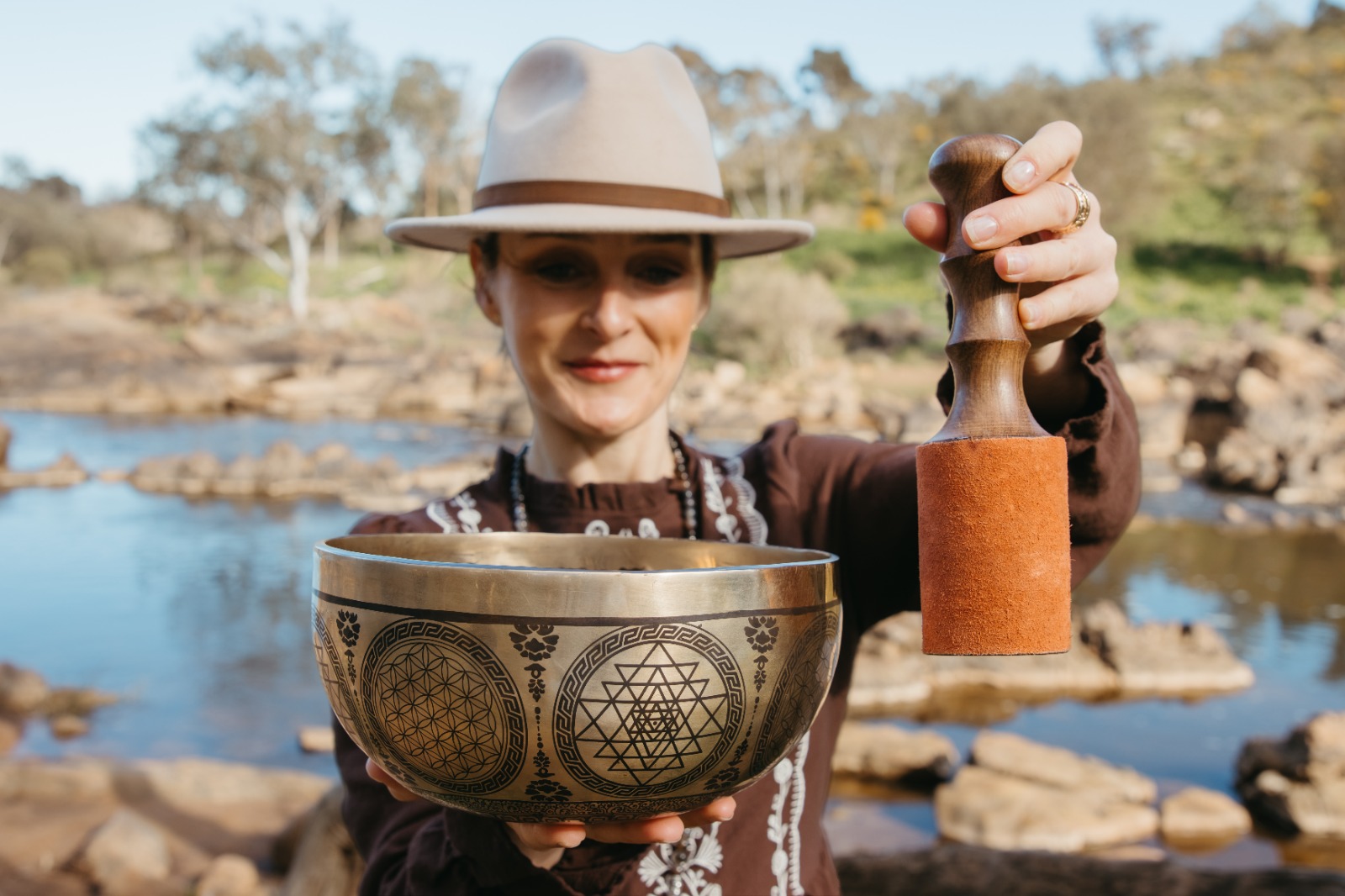 Shana holding a singing bowl by the river