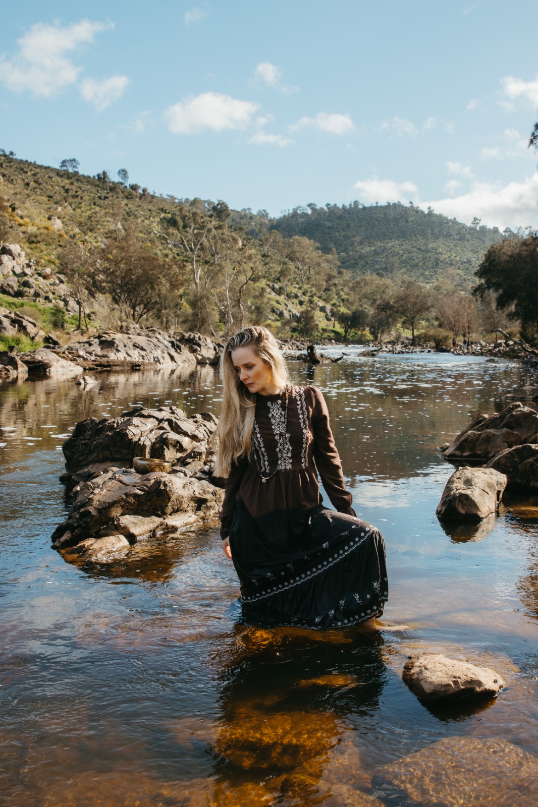 Shana walking beneath an arching gum tree by the river