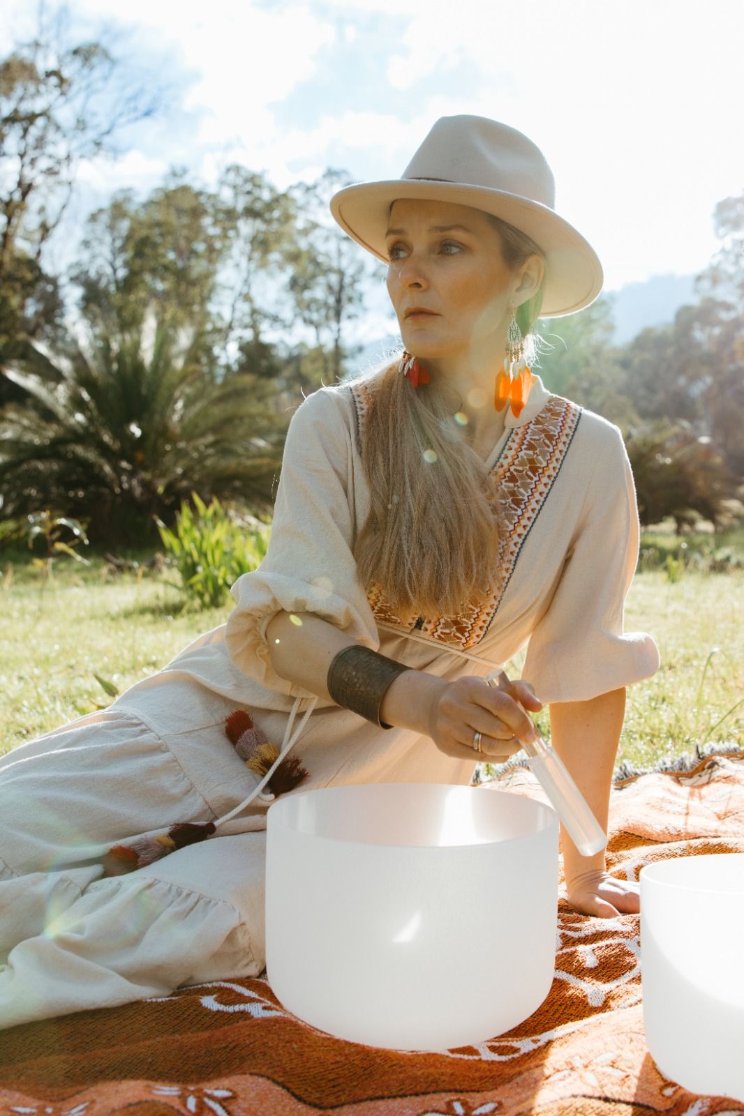 Shana seated with a crystal singing bowl in an open field